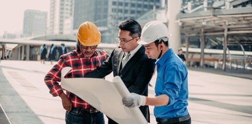 Contractors and a businessman review building plans.