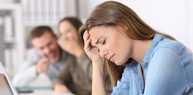 A woman looks upset while onlookers laugh in the background.