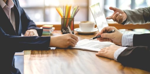 Three business people discuss and sign a contract.