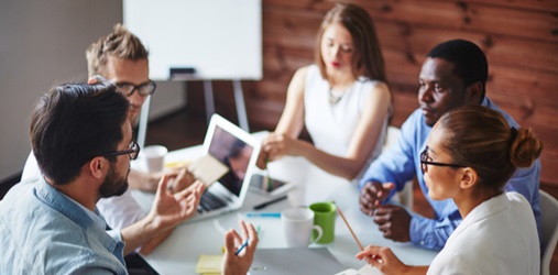 A team of business people meet around a table.