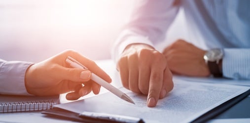 A closeup of two people reviewing a contract.