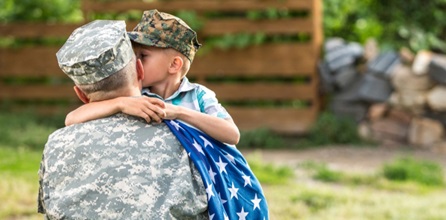 A military father embracing his young son.