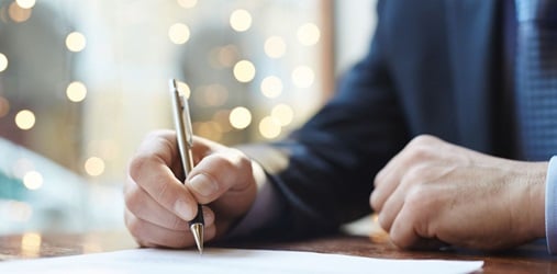 Closeup of a person's hand signing a document.