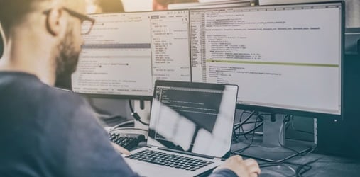 A man working on several screens.