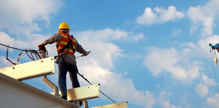 A construction worker standing on a roof.