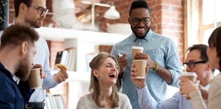 Happy coworkers drinking coffee and laughing.