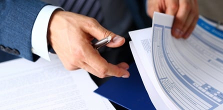 A male arm looking through insurance papers.