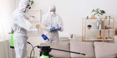 Two cleaners in protective gear using cleaning solution