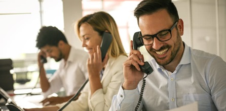 Three cheerful people talking on the phone.