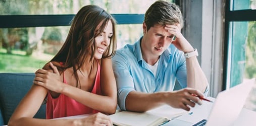 Two people solving a problem on a laptop.