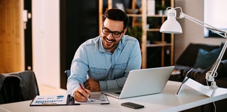 Young businessman working at home with laptop and papers.