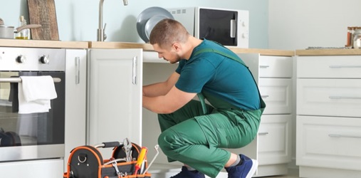 Plumber fixing pipes in kitchen