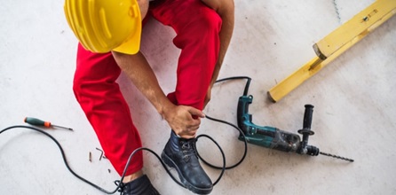 Person holding ankle near construction equipment.