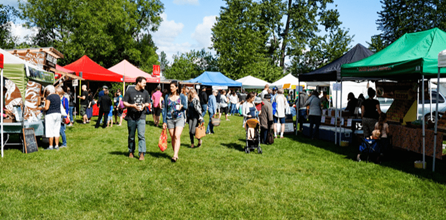 People visiting vendor booths at an outdoor festival.