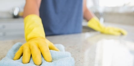 A cleaning professional wipes the counter clean at their client's Airbnb house