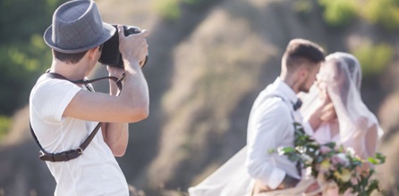 Wedding photographer taking a picture of a bride and groom.