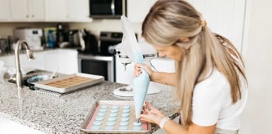 A home baker prepares frosting for a client order 