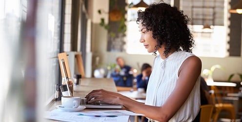 Woman reviewing business charts in coffee shop.