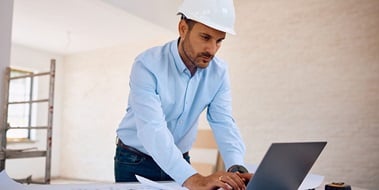 Contractor reviewing documents on a laptop computer.