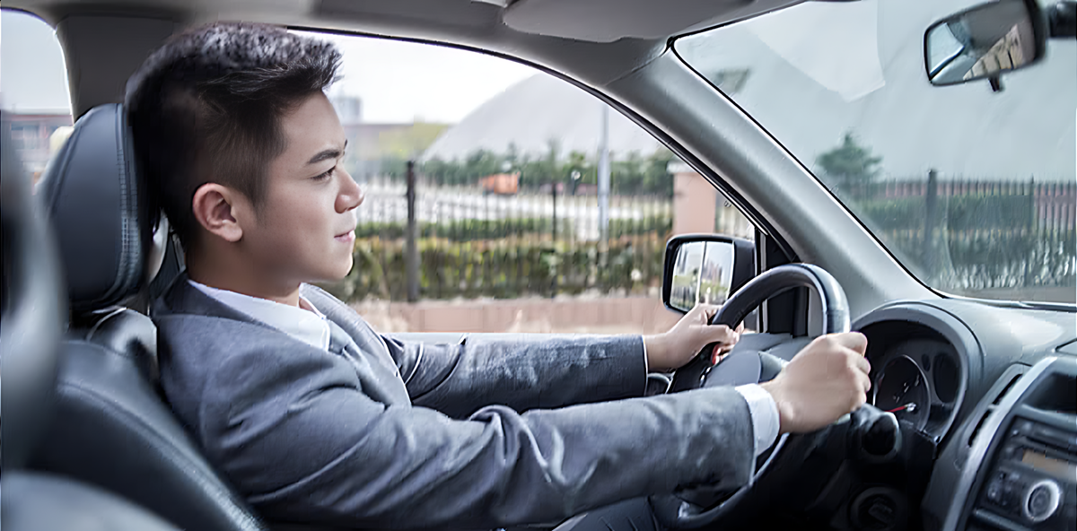 Businessman in a gray suit driving a car.