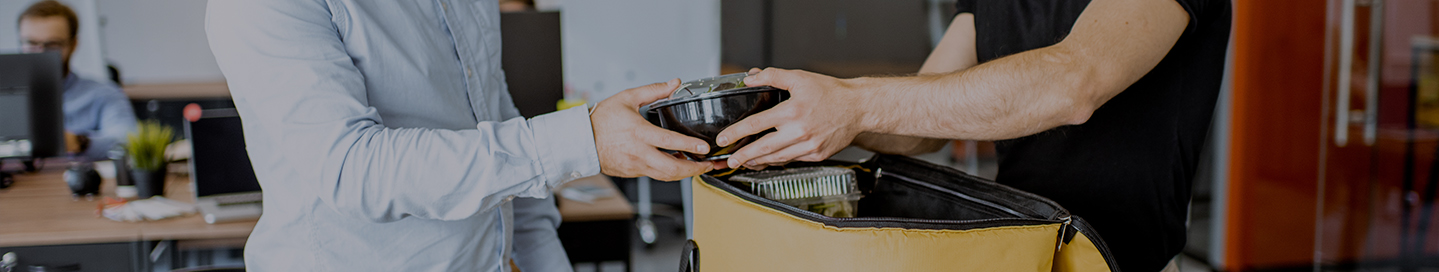 A delivery driver hands a customer their takeout meal. A delivery driver hands a customer their takeout meal.