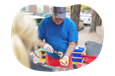 Employee assembling hot dog at their hot dog cart.