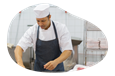 A butcher in an apron cutting up meat.