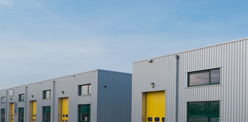 Exterior of commercial warehouses with yellow roller doors.