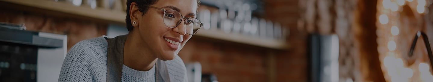 A small business owner is working on a computer in a cafe. A small business owner is working on a computer in a cafe.